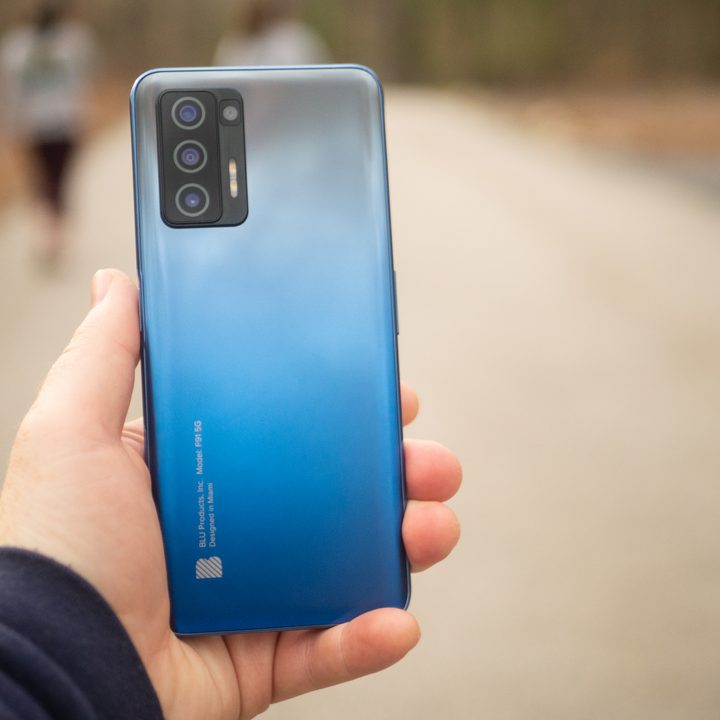 Hand holding a Blu F91 5G with a road going off in the background