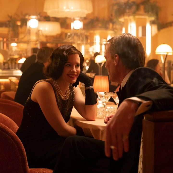 Claire Foy sits at a dinner table with Paul Bettany in A Very British Scandal.