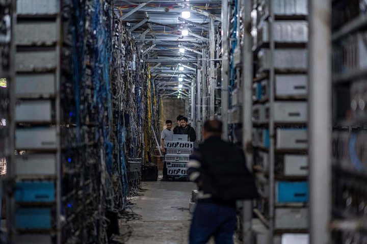 Workers transfer cryptocurrency mining rigs at a cryptocurrency farm .