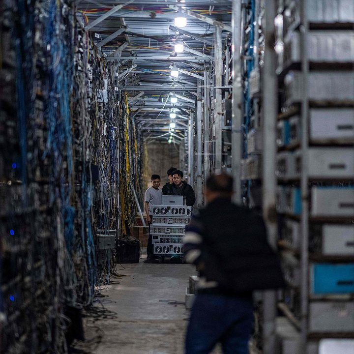 Workers transfer cryptocurrency mining rigs at a cryptocurrency farm .