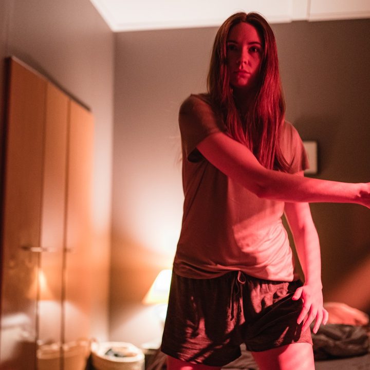 Karen Gillan wields a knife while lit by a red light in a scene from Dual.