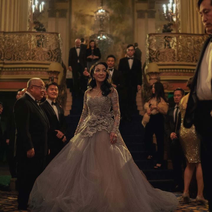Evelyn Wang stands in a theater foyer in Everything Everywhere All At Once.