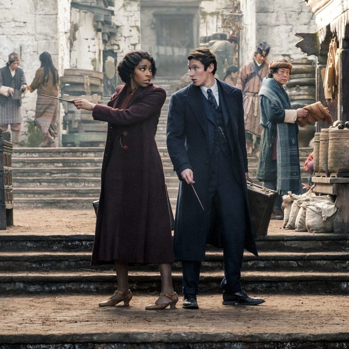Jessica Williams and Callum Turner stand back-to-back in a street in Fantastic Beasts 3.