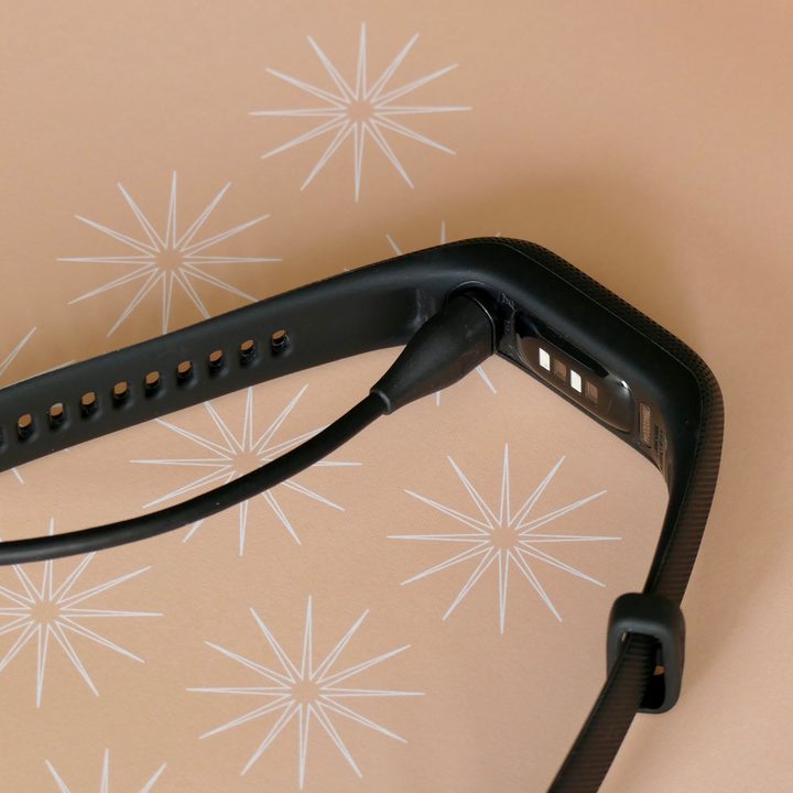 Garmin Vivosmart 5's proprietary charge cable plugged in.