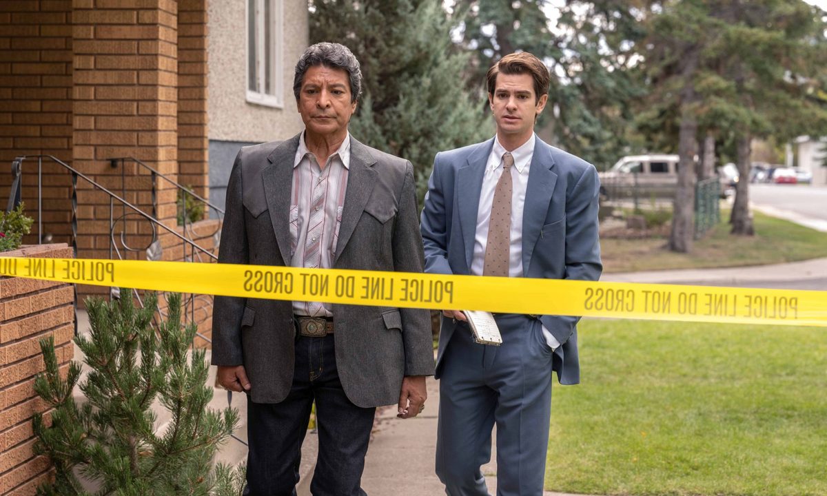Gil Birmingham and Andrew Garfield walk toward crime scene tape in Under the Banner of Heaven.