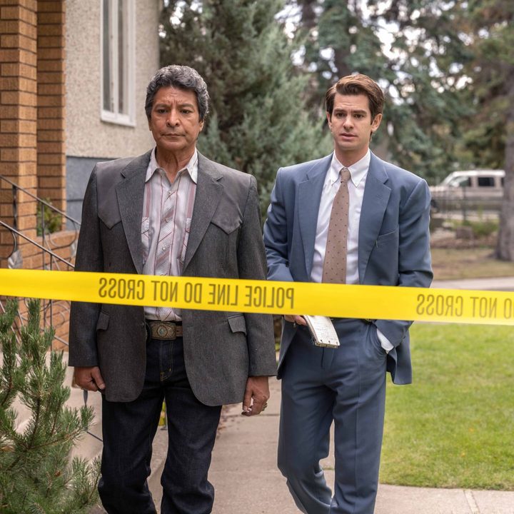 Gil Birmingham and Andrew Garfield walk toward crime scene tape in Under the Banner of Heaven.