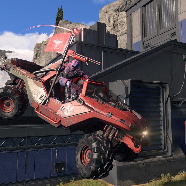 A Spartan holds the enemy flag while riding a Warthog in Halo Infinite.