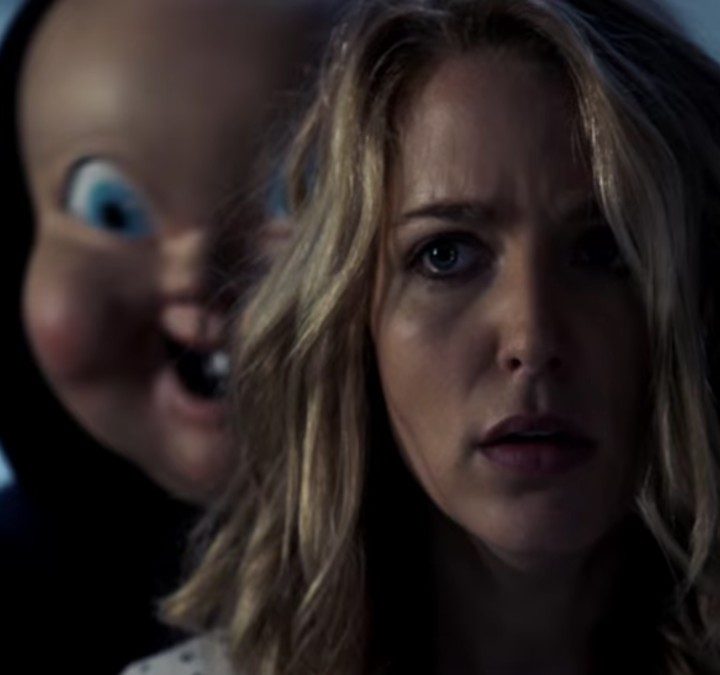 A killer stands behind a blonde woman in Happy Death Day.