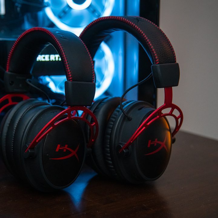 Two HyperX Cloud Alpha Wireless headsets leaning against a PC.