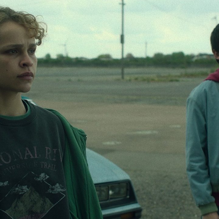 Iola Evens and Asa Butterfield stand outside a car in an empty parking lot in Choose Or Die.