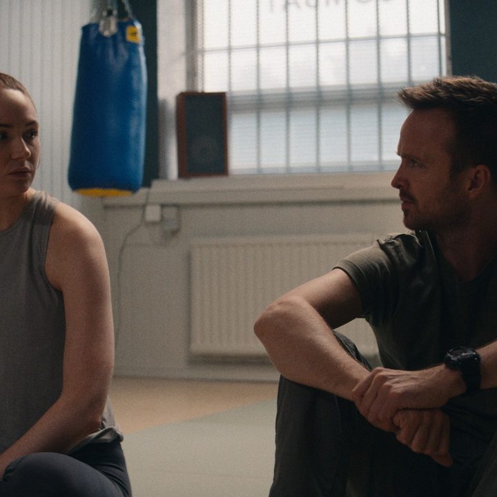 Karen Gillan and Aaron Paul talk while seated on the floor in a scene from Dual.