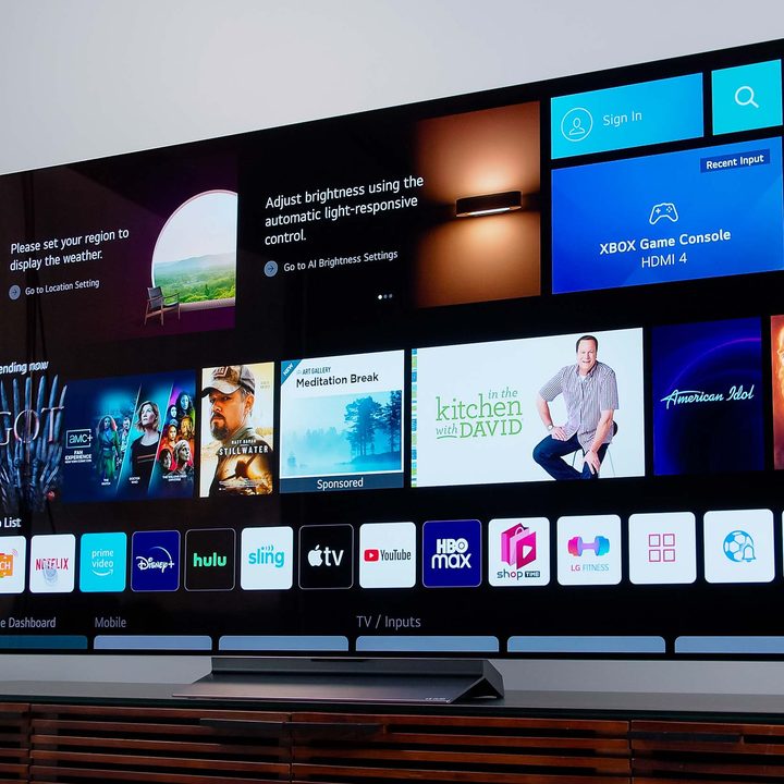 The LG C2 OLED with the home dashboard displayed sits on an entertainment stand.