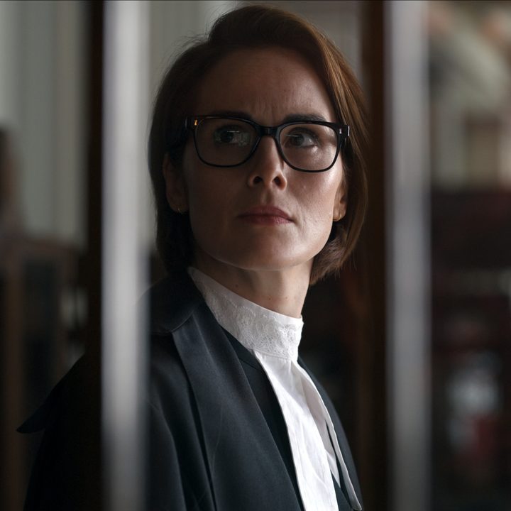 Michelle Dockery stands behind bars wearing a Barrister gown in Anatomy of a Scandal.