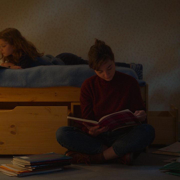 Nelly's mother sits on the floor near her daughter's bed in Petite Maman.