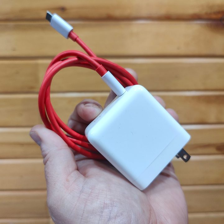 A hand holds the OnePlus 10 Pro charging brick.