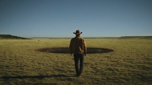 Josh Brolin walks toward a massive, mysterious hole in the ground in a scene from Outer Range.