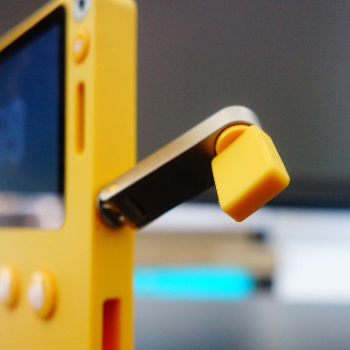 The Playdate's crank protrudes from the handheld.