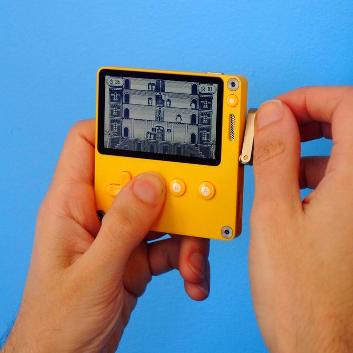 A gamer holds a Playdate in their hands.