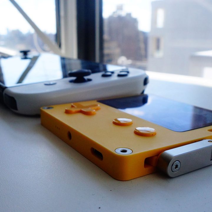 A Playdate and Switch OLED sit side by side on a table.