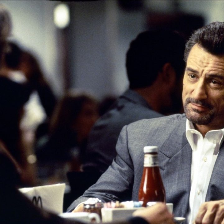 Robert De Niro smiles while looking at Al Pacino in Michael Mann's Heat.