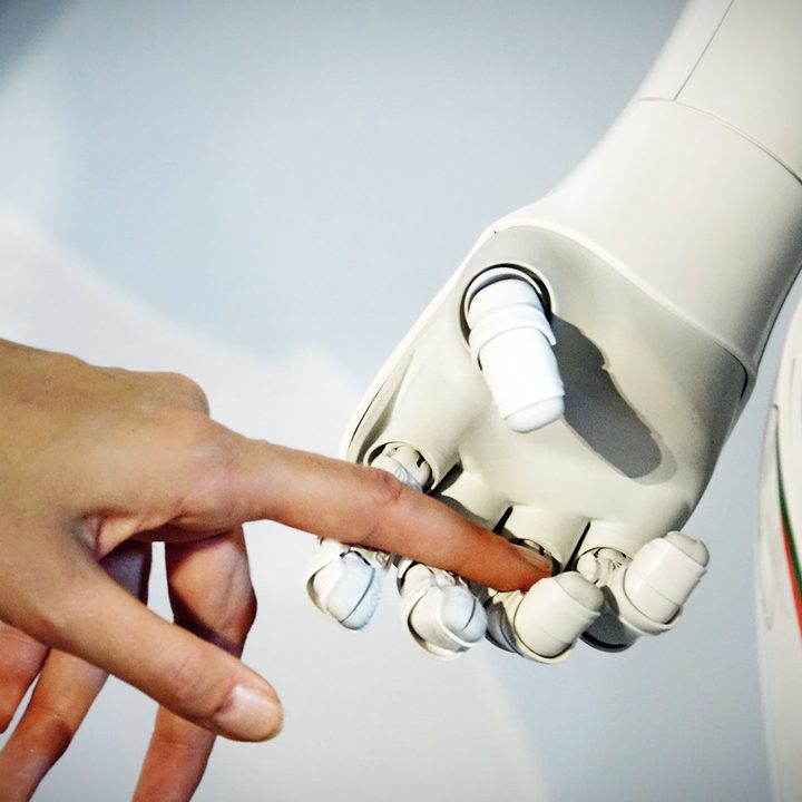 A woman's hand is held by a robot's hand.