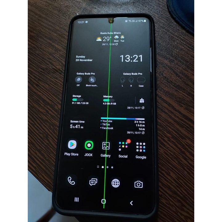 Samsung Galaxy S20 Plus with a defective display showing a green line running in the middle is kept on a table.
