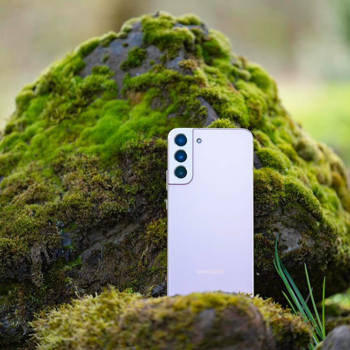 The Samsung Galaxy S22+ sitting on a moss covered rock.