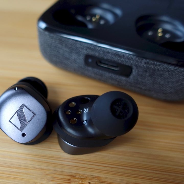 Sennheiser Momentum True Wireless 3 sitting beside their charging case.