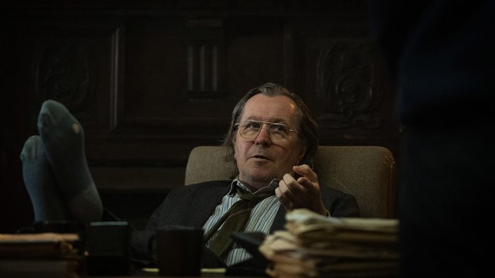 Gary Oldman reclined back in an office chair, feet on his desk in a scene from Slow Horses on Apple TV+.