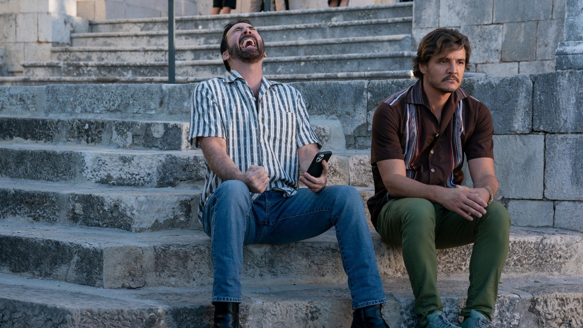 Nicolas Cage laughs while Pedro Pascal worries.