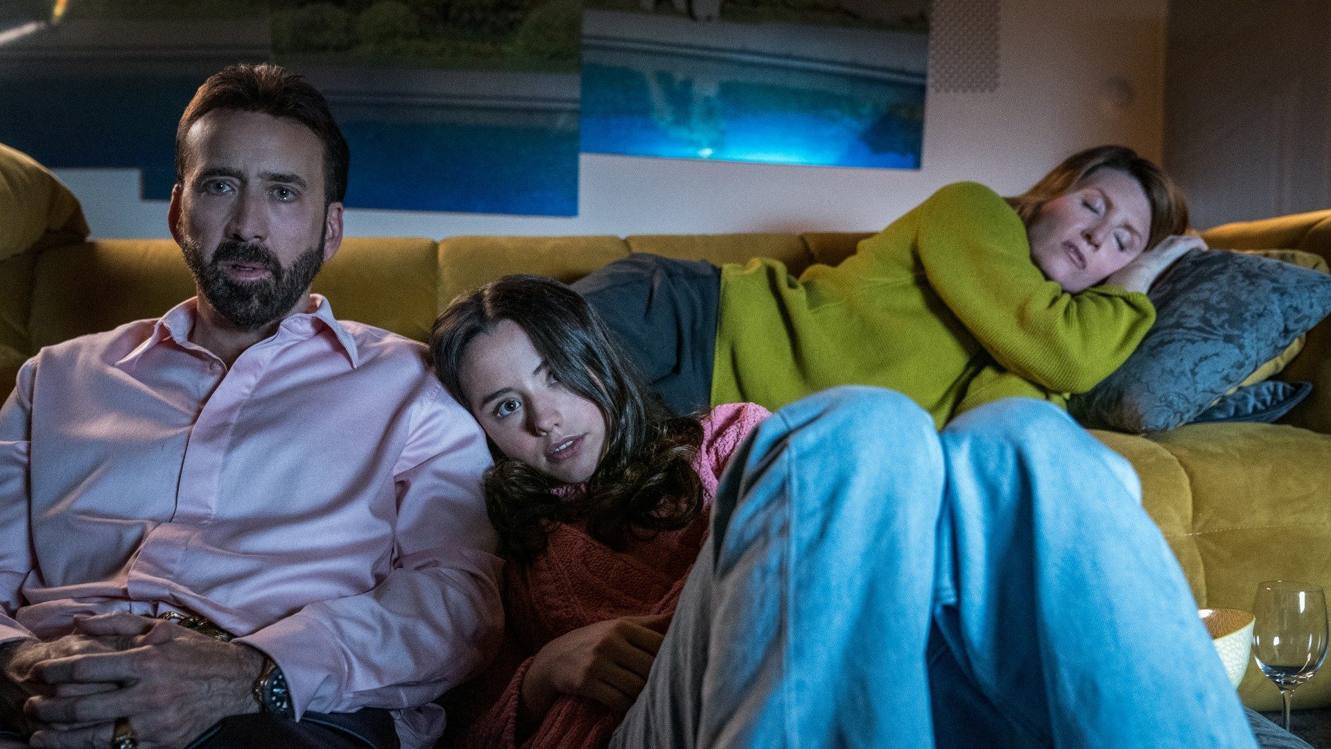 Nicolas Cage and Lily Mo Sheen watch a movie while Sharon Horgan sleeps behind them.