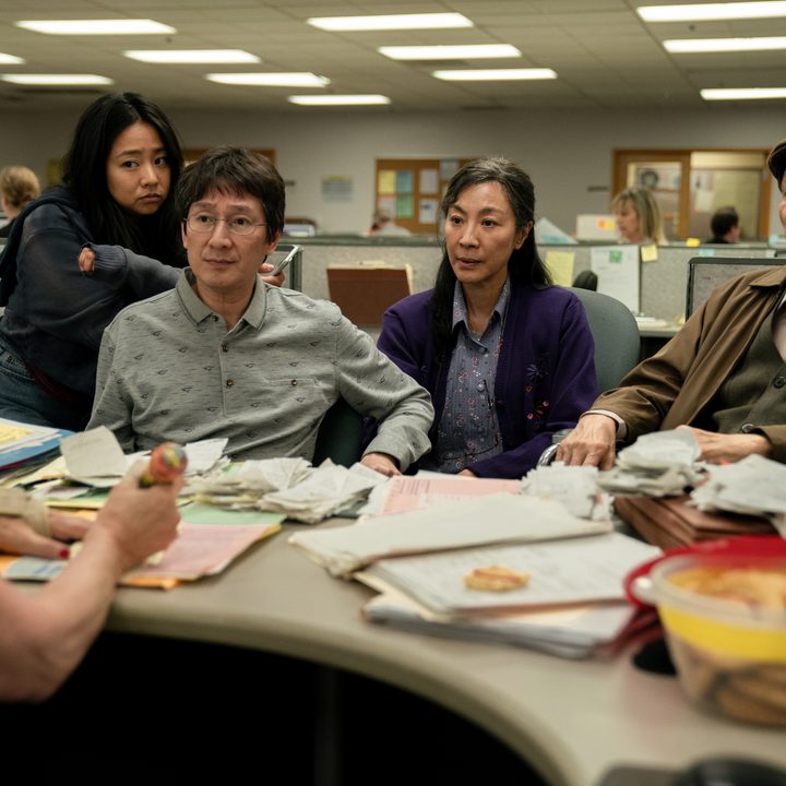 The Wangs sit together in front of an IRS auditor's desk in Everything Everywhere All At Once.