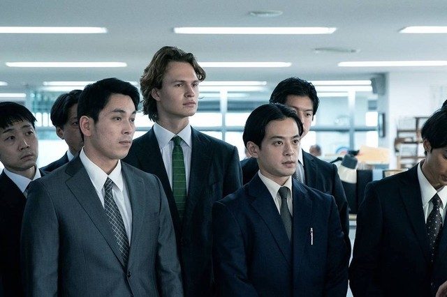Ansel Elgort stands in a crowd of reporters in a scene from Tokyo Vice.
