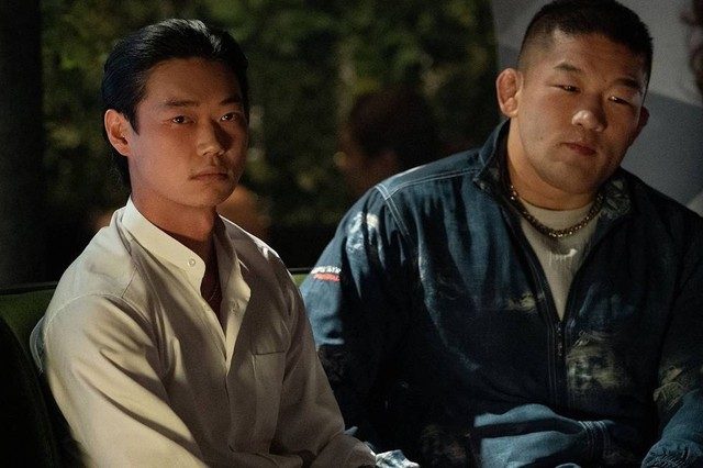 Sho Kasamatsu sits at a table next to a large henchman in a scene from Tokyo Vice.