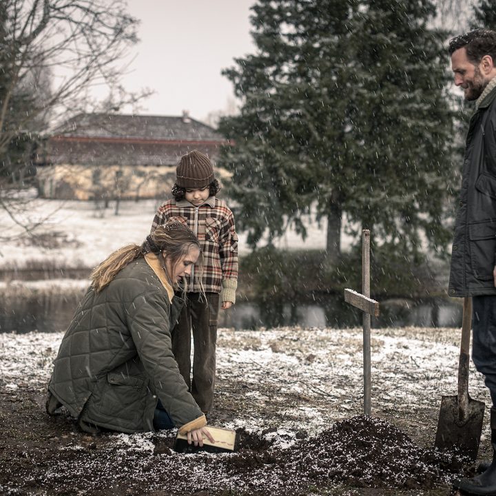 Rachel, Elliot, and Anthony stand in front of a burial ground in a scene from The Twin.