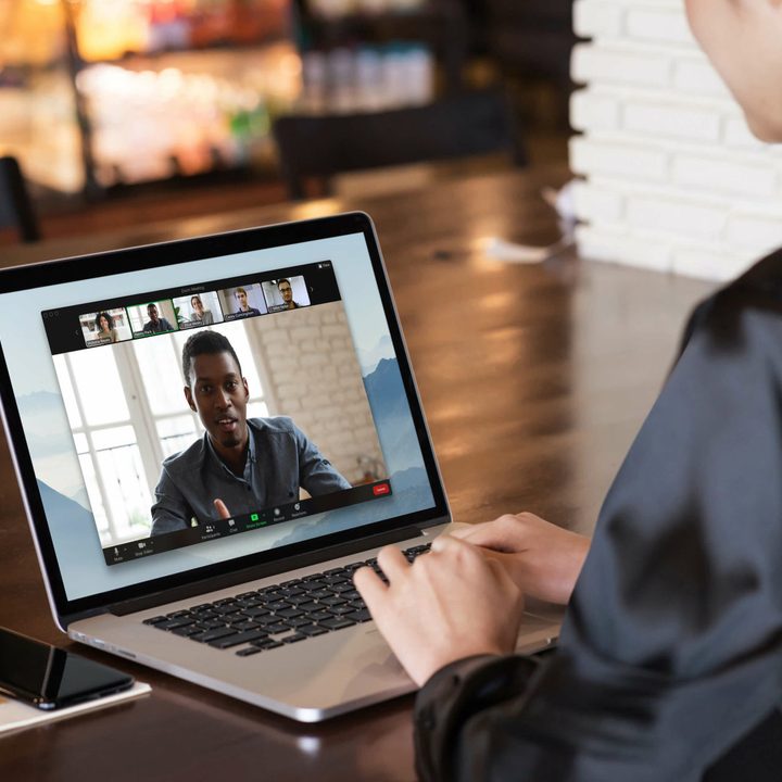 A person conducting a Zoom call on a laptop while sat at a desk.