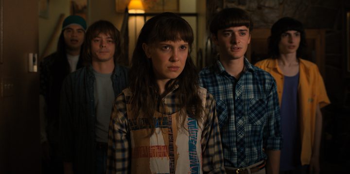 Eleven, Will, Mike, and Jonathan standing and staring in a still from Stranger Things Season 4.