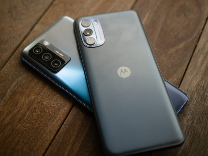 Moto G 5G smartphone sitting on top of a Blu F91 5G smartphone on a wooden table