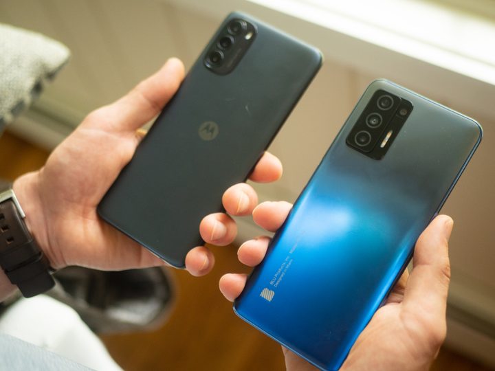A person holding a Moto G 5G and Blu F91 5G smartphone in each hand