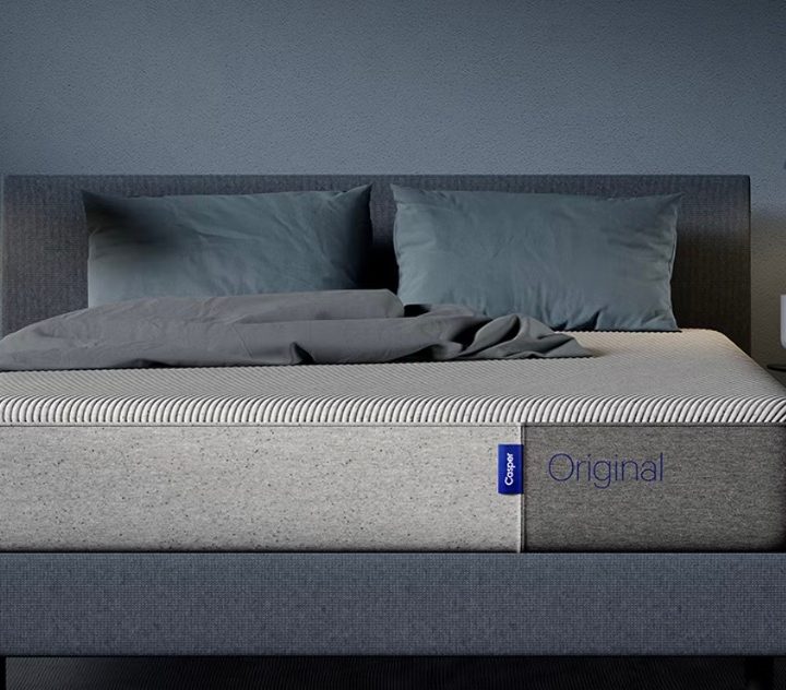 The Casper Original mattress sits on a bed frame in a blue bedroom.