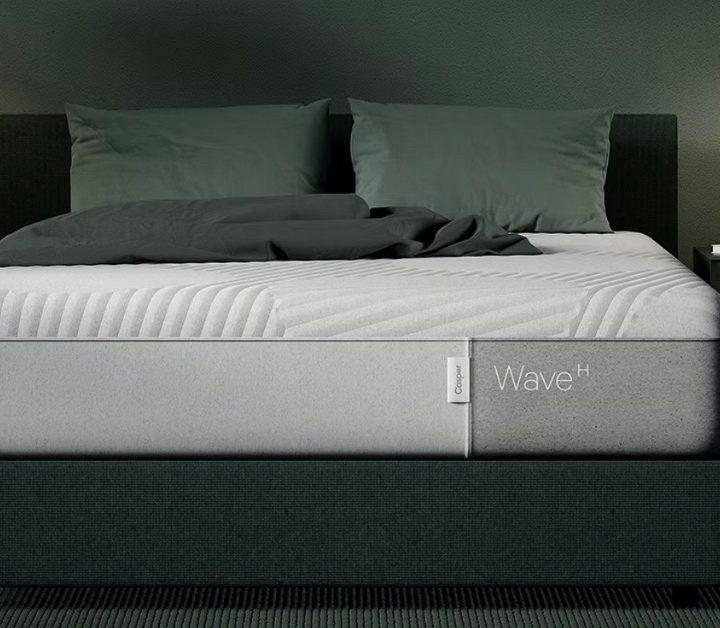 A Casper Wave Hybrid mattress sits on a bed frame in a green bedroom.