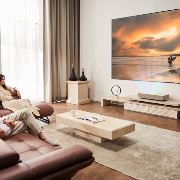 A couple watching an image displayed by the LG CineBeam HU915QE ultra short throw 4K laser projector.