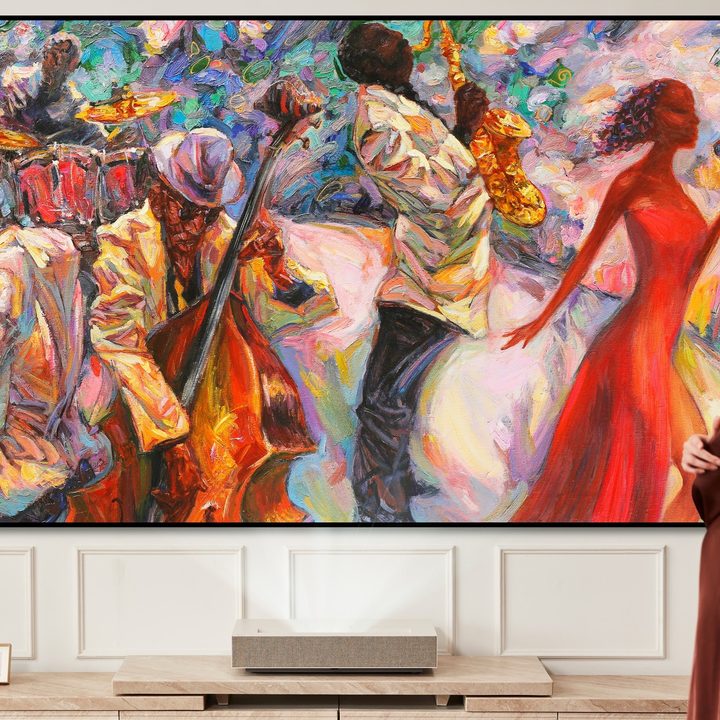LG CineBeam HU915QE ultra short throw 4K laser projector seen beside a woman.