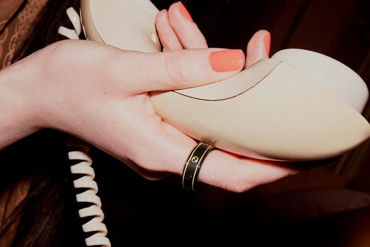 Person wearing the Gucci x Oura Ring and holding a telephone.
