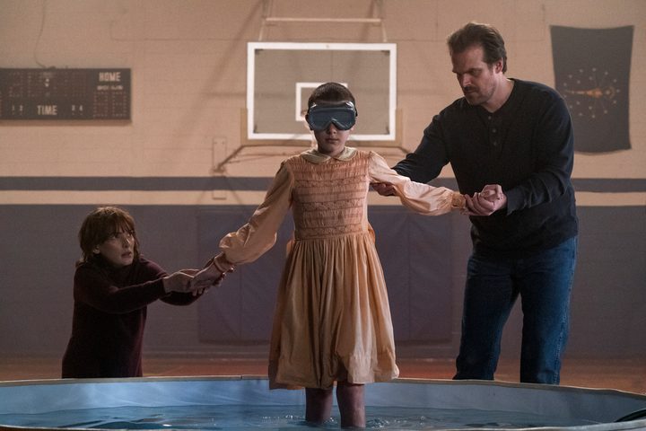 Winona Ryder, Millie Bobby Brown and David Harbour in a gym in Stranger Things.