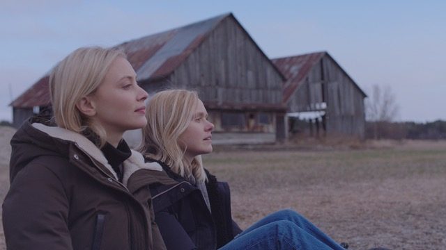 Elf and Yoli sit down outside and look into the distance in a scene from All My Puny Sorrows.