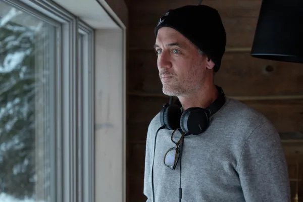 Director Michael Gadon stares out the window with headphones around his neck from the set of All My Puny Sorrows.
