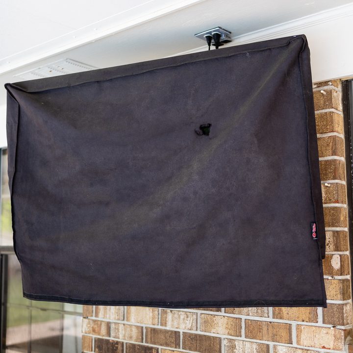 A TV mounted outdoors with a cover.