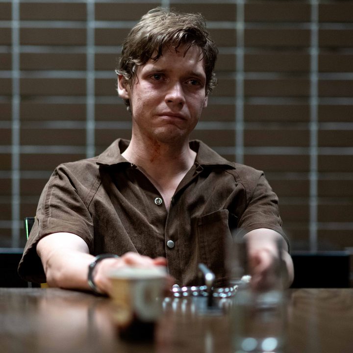 Billy Howle sits handcuffed to a table in Under the Banner of Heaven.