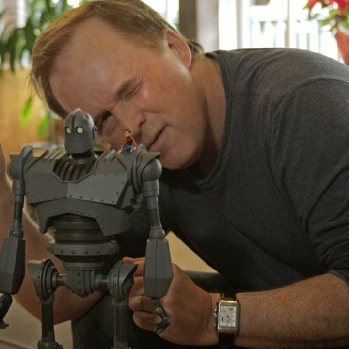 Brad Bird sitting behind a model of the Iron Giant.